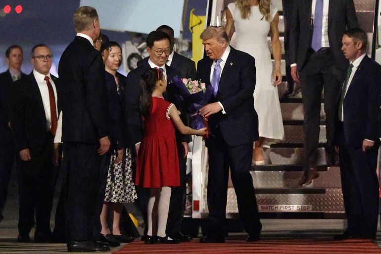 BEIJING, CHINA - MAY 13: U.S. President Donald Trump (C) receives a flower bouquet from a young girl as Vice President of China Han Zheng looks on upon his arrival at Beijing Capital International Airport on May 13, 2026 in Beijing, China. President Trump is meeting with President Xi Jinping in Beijing to address the Iran conflict, trade imbalances, and the Taiwan situation while establishing new bilateral boards for economic and AI oversight. (Photo by Alex Wong/Getty Images)
