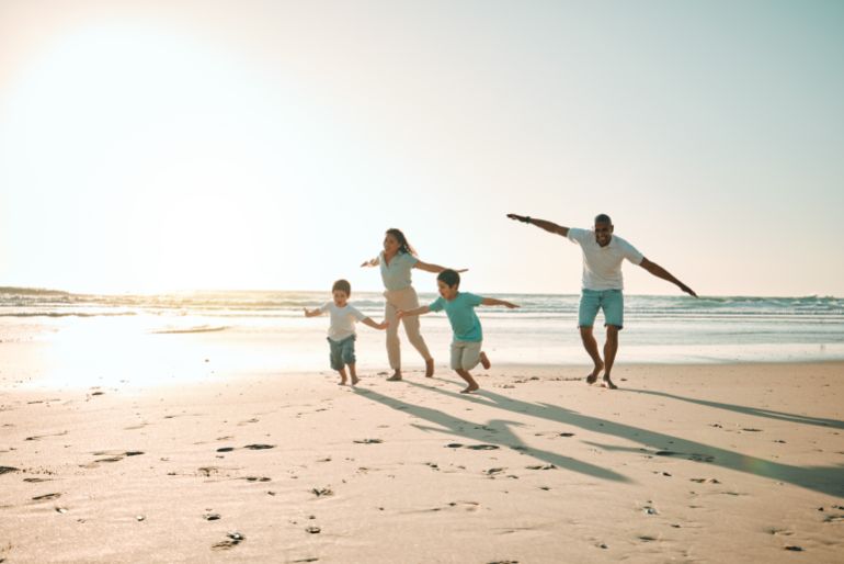 Beach, run and airplane by family playing, freedom and happy along the ocean on blue sky background. flying, game and children running with parents in Mexico for travel, trip and summer vacation - stock photo