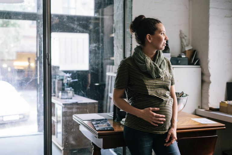 Pregnant woman talking a break while working in Roastery