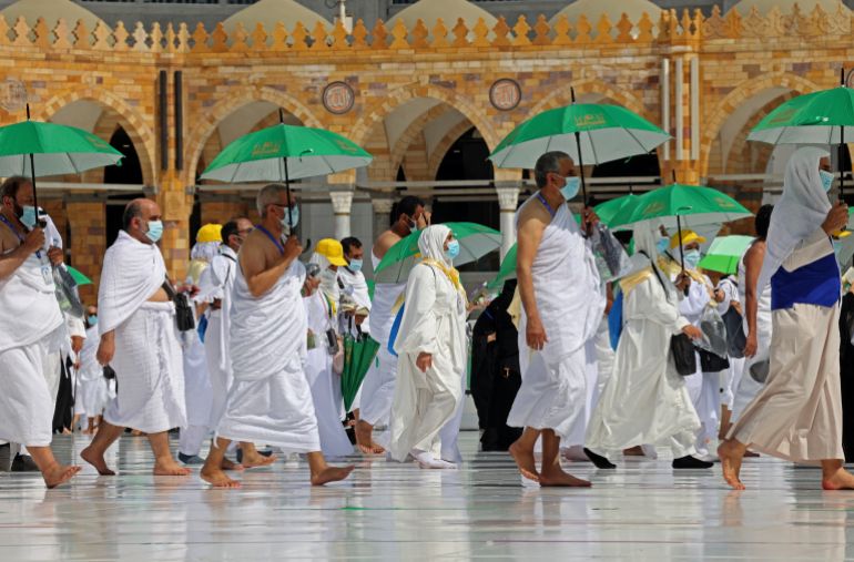 hajj1-1778752135 Pilgrims holding umrellas to protect themselves from the heat, arrive at the Kaaba, Islam's holiest shrine, at the Grand mosque in the holy city of Meccca, at the start of the Hajj season, on July 17, 2021. Saudi Arabia hosts another downsized hajj from July 17, with only residents fully vaccinated against the coronavirus permitted and overseas Muslim pilgrims barred for a second year. The annual ritual is a central pillar of Islam and a must for able-bodied Muslims at least once in their lifetime. (Photo by Fayez Nureldine / AFP)