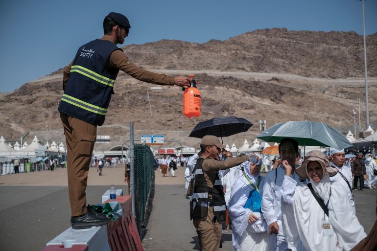 hajj3-1779272422 MINA, KINDOM OF SAUDI ARABIA (KSA)-JUNE 29, 2023 : Unidentified Saudi policemen spray water to Indonesian hajj pilgrims in Mina. Pilgrims are advised to drink lots of water to prevent heat stroke.