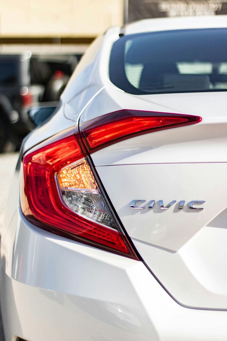 hwnda-1778321902-1 Detailed shot of a white Honda Civic's tail light and logo in daylight.
