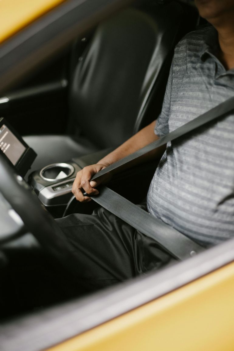 hzam-alaman-1778936736 Close-up of a man fastening his seatbelt in a car, emphasizing safety and modern automotive interior.