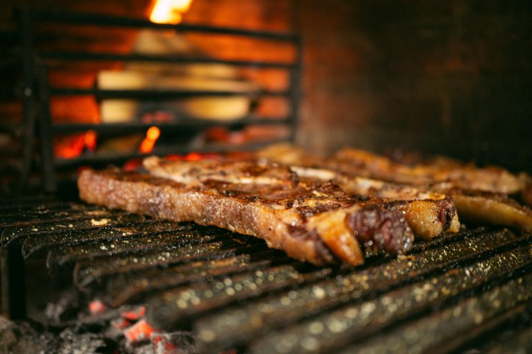 Close-up of a juicy steak grilling over charcoal fire for a smoky, savory flavor experience.