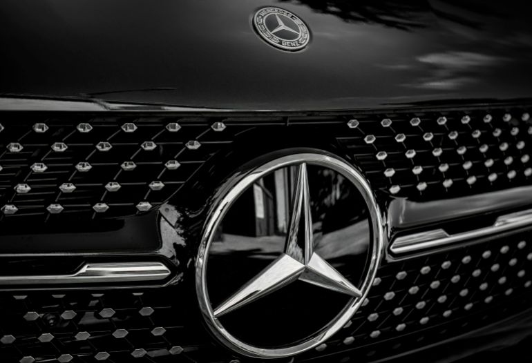 Detailed close-up of a Mercedes-Benz emblem on a luxury vehicle in black and white.