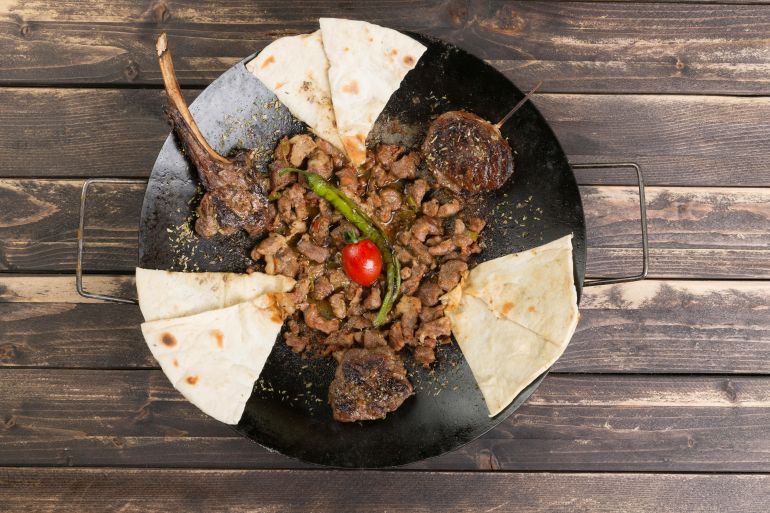 Delicious mixed grill served with flatbread on a rustic wooden table, perfect for a traditional Turkish meal.