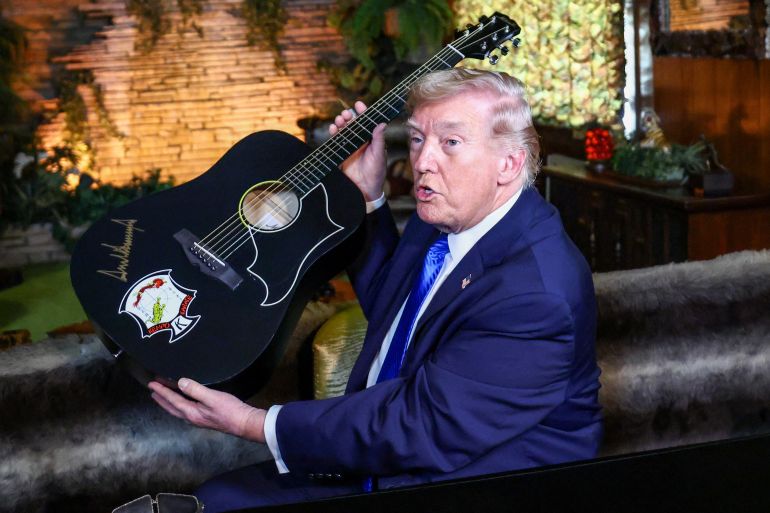 ترمب في بيت ألفيس بريسلي U.S. President Donald Trump holds a replica of a guitar after signing it during a visit to Graceland, the home of Elvis Presley, in Memphis, Tennessee, U.S., March 23, 2026. REUTERS/Kevin Lamarque TPX IMAGES OF THE DAY