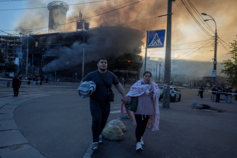 reuters_6a1309b5-1779632565 People walk near a burning building as they leave a shelter after overnight Russian missile and drone attacks, amid Russia's attack on Ukraine, in Kyiv, Ukraine, May 24, 2026. REUTERS/Thomas Peter TPX IMAGES OF THE DAY