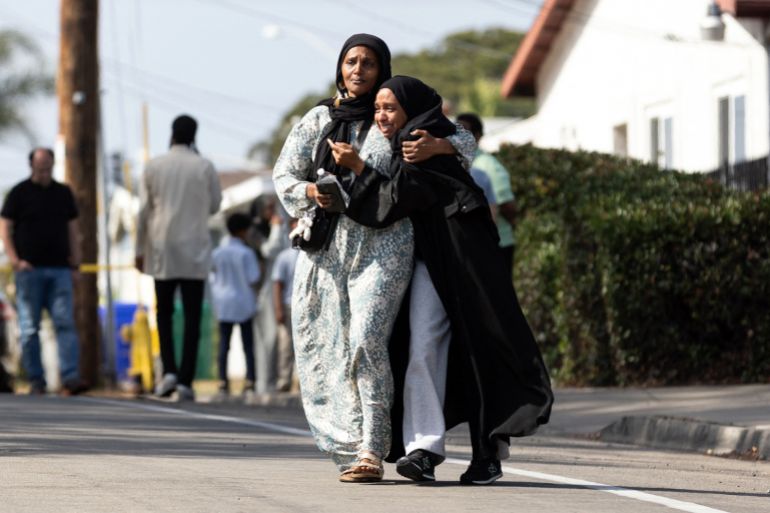 Two women cry as they leave a reunification center following the shooting at the Islamic Center of San Diego in southern California, on May 18, 2026. A shooting at the largest mosque complex in San Diego killed three people, with two suspected teenage gunmen later found dead in a car from self-inflicted gunshot wounds, police said. (Photo by Zoë Meyers / AFP)