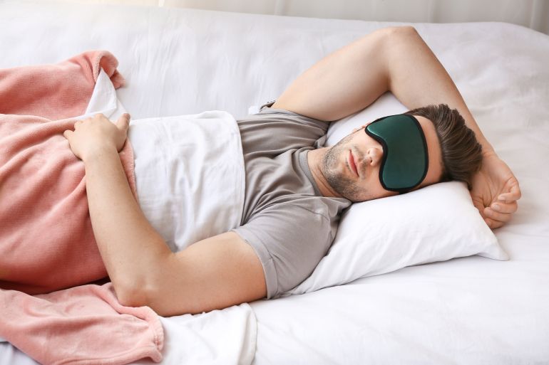 Young man with mask sleeping in bed