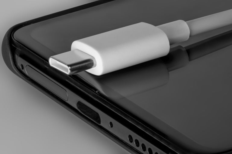 shutterstock_1498058339-1779715839 usb-4 cable white new with a black phone. new technologies in smartphones.