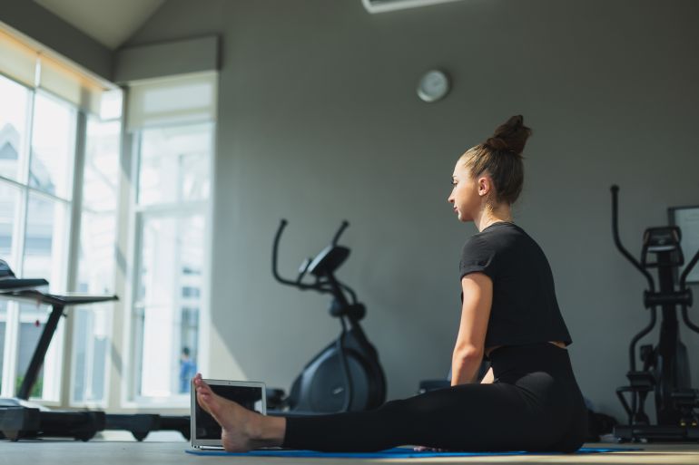 Female sportswear yoga in gym, Woman training at fitness watching videos on laptop. healthcare lifestyle concept.