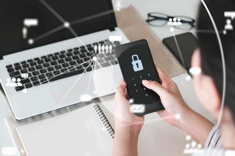 shutterstock_2010318071-1779875371 Hacking a Phishing mobile phone with a password to access a smartphone, security threats online, and fraud. A young man with a cell phone and laptop is secure in his bank account.