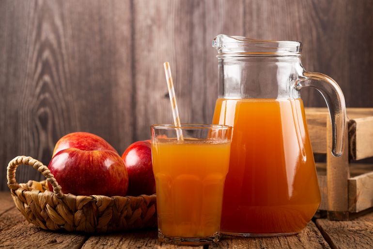 Apple juice and red apples on the table.