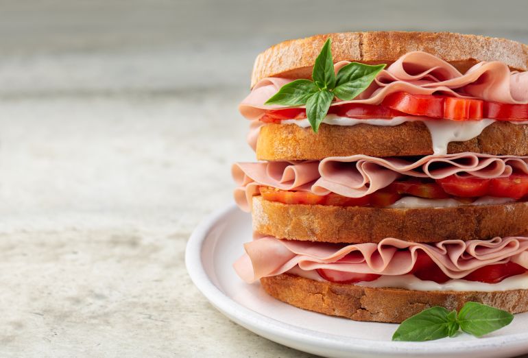 Close-up of italian deli sandwich with mortadella, soft cheese Stracchino and tomatoes.. Copy space., closeup,