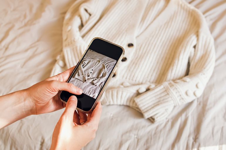 Close-up of woman's hands taking picture of her clothes. Selling used clothes online, reuse, sustainable consumption
