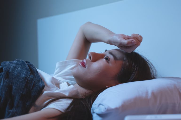 Asian women opened eyes lying on the bed have an insomnia problems.