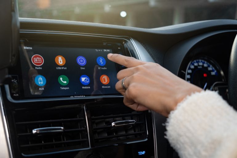 Bandung, Indonesia - August 17, 2023: Someone is operating the radio or music using the touch screen on the car audio system. bluetooth technology
