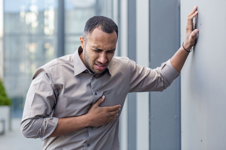 Man experiencing chest pain outdoors, clutching his heart in distress, concept of heart attack, health emergency; Shutterstock ID 2412878225; purchase_order: aj; job: ; client: ; other: