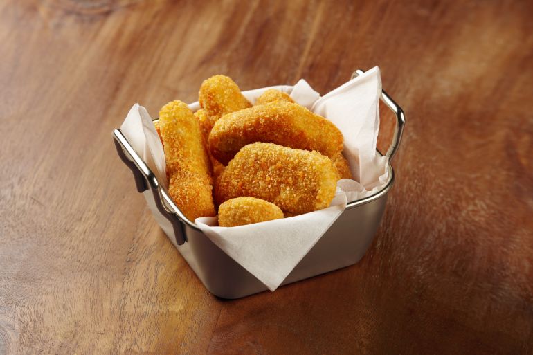 shutterstock_2460726809-1779265486 A portion of chicken nuggets in a unique tin container in the middle of a wooden table