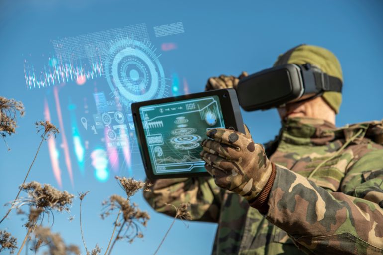 AI technology in the army. Warfare analytic operator using vr virtual reality glasses checking coordination of the military team with tablet device augmented reality operating troops outdoors