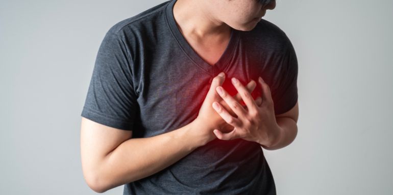 heart disease concept. man pressing on chest with painful expression. severe heartache and having heart attack or painful cramps.