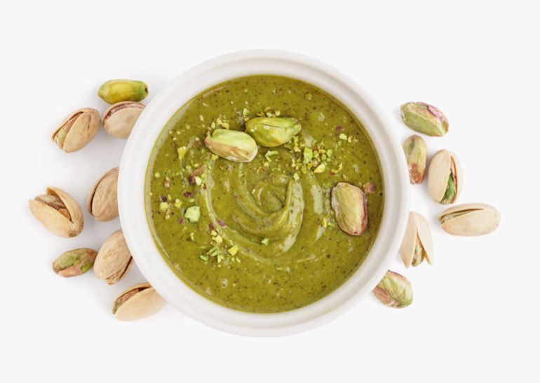 shutterstock_2492706153-1779705587 Bowl with pistachio paste on white background كريمة الفستق