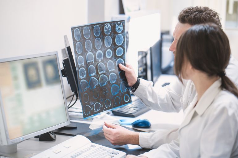 two doctors man and woman doctor examine an MRI image of the brain in an MRI room. Blurred image
