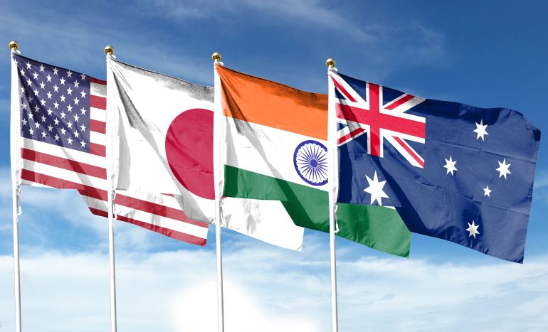 shutterstock_2522169397-1779220706 ***للاستخدام الداخلي*** The American and Japanese flags are textured as are the Australian and Indian flags. Concept map depicting the dialogue between the leaders of the four countries. Double exposure hologram.