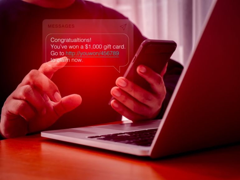 SMS spam, fake text message phishing from scammer concept. Spam text messages, Winning congratulations phishing text with link tracking, on message alert display on mobile phone screen in person hand.
