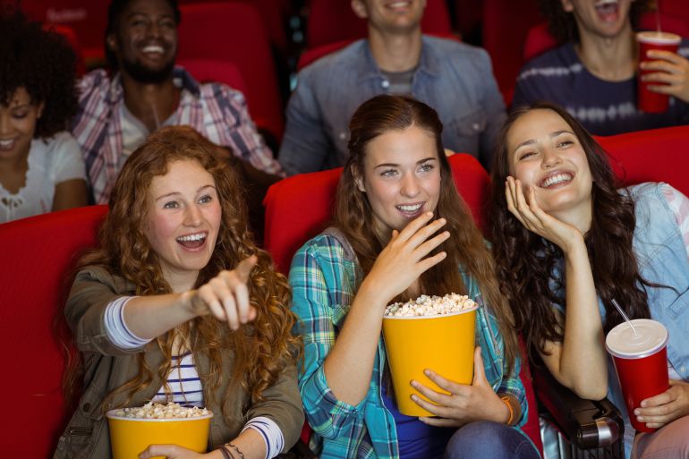 Young friends watching a film at the cinema