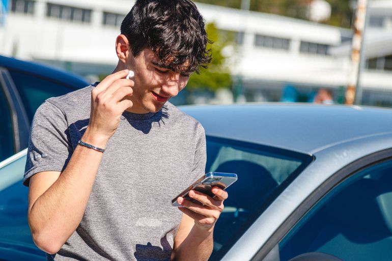 casual young man listening to music with headphones on the street