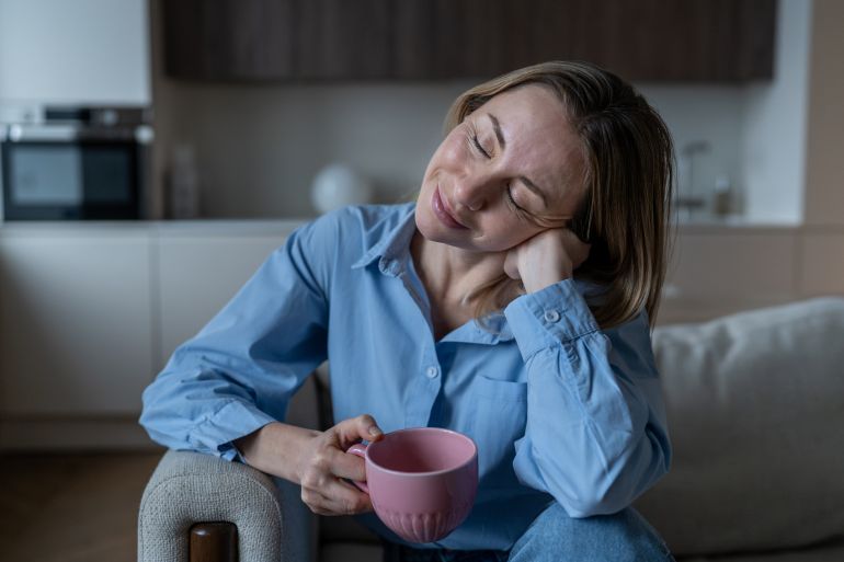 shutterstock_2687481825-1778411089 Happy midlife woman resting on home sofa smiling with pleasure closed eyes enjoying coffee break