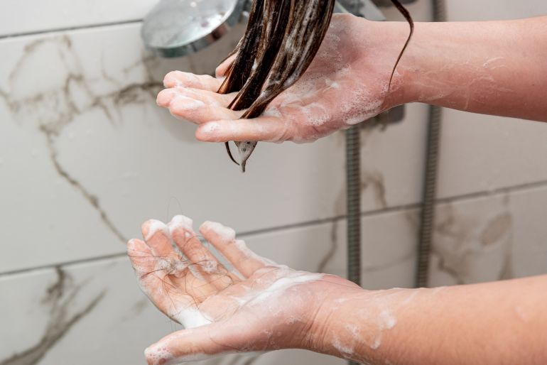 shutterstock_2705027709-1780216950 Young woman washing head in shower, long hair loss, care and wellness relaxation