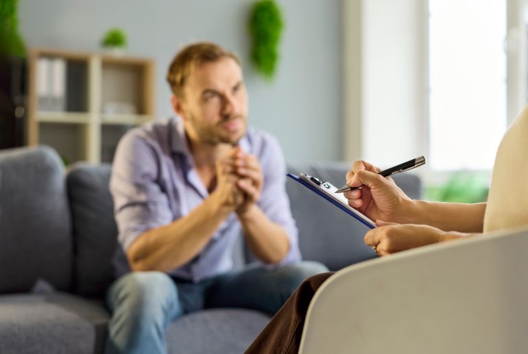 Therapist and patient in counseling therapy session. The therapist listens, writes notes, and guides the conversation, offering mental support and advice. Concept: trusted mental health care.