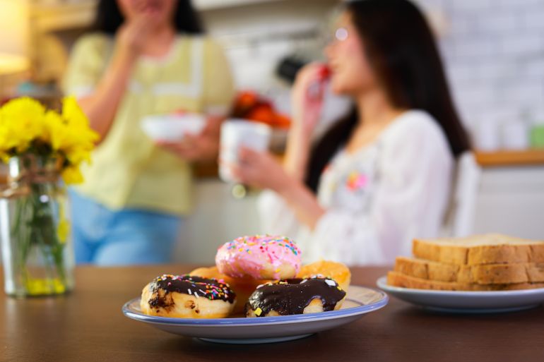 Assorted donuts and toast on plates, unhealthy breakfast or snack. Concept of junk food, obesity risk, and poor eating habits.