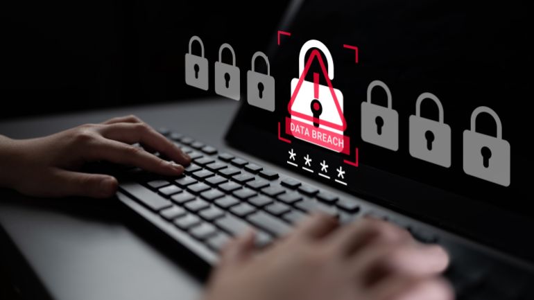shutterstock_2763765297-1779636103 A person typing on a keyboard with a warning symbol on the screen signaling a data breach. This image highlights the importance of cybersecurity in today digital age. Ledger
