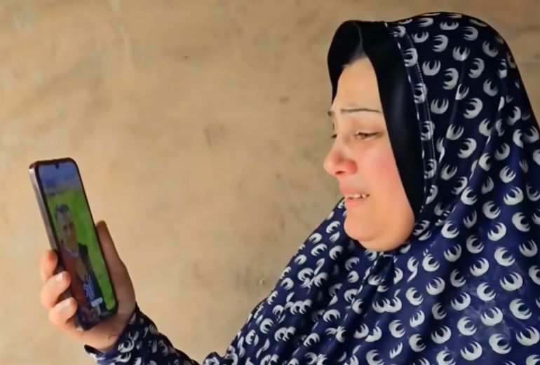 Gaza mother Maha Abu Shaar holds her phone displaying a photo of her son Eid as she cries with joy and sadness after discovering he is alive but in an Israeli prison [Screengrab/Al Jazeera]
