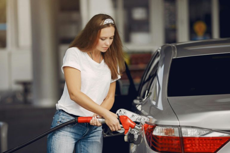 A close-up view of a fuel pump nozzle inserted into a car's tank at a gas station.