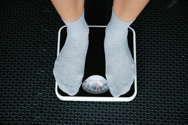 Top view of feet in socks standing on a bathroom scale, indicating weight measurement