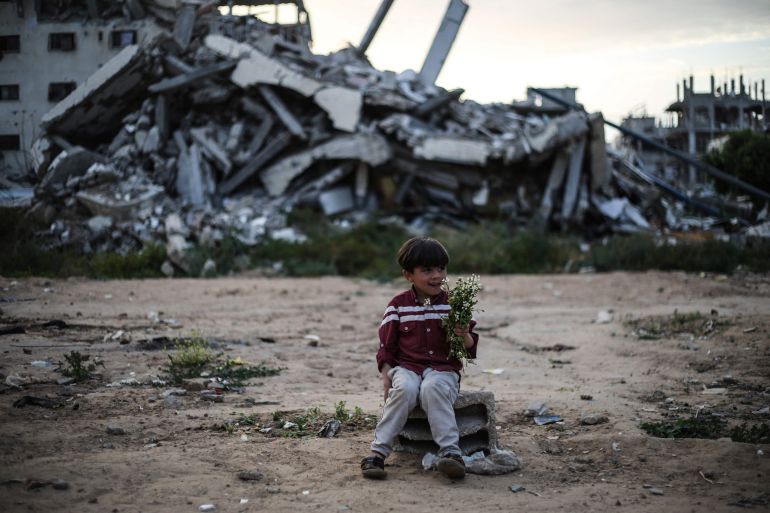 A Palestinian boy sitting on a breeze block in front of destroyed buildings, holds a bunch of spring flowers in the Bureij Palestinian refugee camp in the central Gaza Strip on May 2, 2026. The war on the Gaza Strip was sparked following the militant Palestinian group Hamas's October 7, 2023 attack on Israel, which resulted in the deaths of 1,221 people. Israel's retaliatory assault on Gaza has killed at least 72,600 people, according to figures from the health ministry that the UN considers reliable, with the majority of Gaza's 2.4 million people being displaced. (Photo by Eyad Baba / AFP via Getty Images)