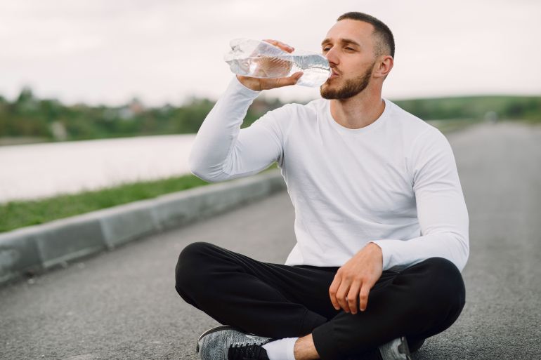 02-2-1781514061 A man in sportswear hydrates outdoors, promoting healthy lifestyle and fitness.