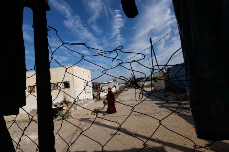 A woman walks as displaced Palestinians who fled their homes due to Israeli strikes shelter at Rafah crossing on the border with Egypt, amid the ongoing conflict between Israel and the Palestinian Islamist group Hamas, in Rafah in the southern Gaza Strip, December 8, 2023. REUTERS/Mohammed Salem