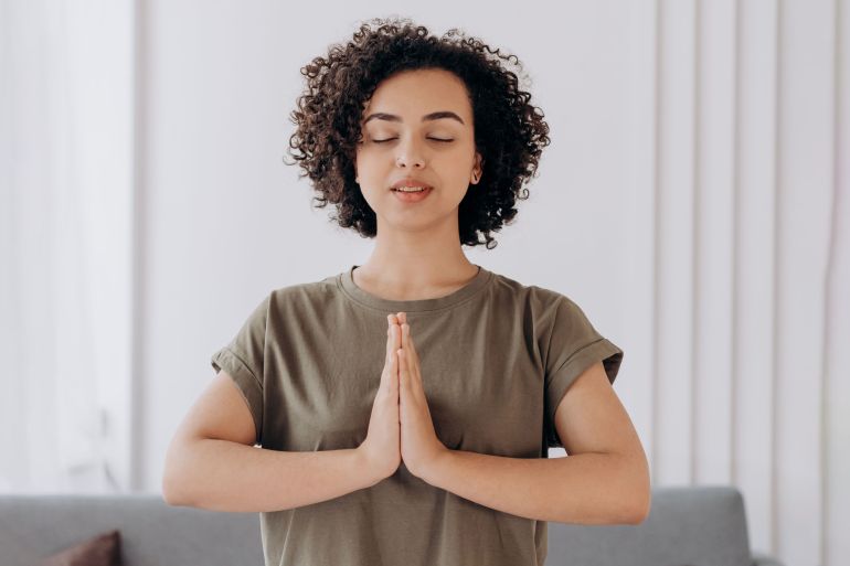 3453435-1781689907 A woman meditating at home with closed eyes, enjoying tranquility and relaxation.