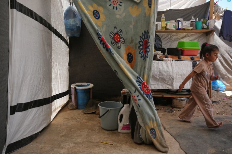 Wateen Darwish walks past her family’s makeshift toilet at a camp for displaced Palestinians in Khan Younis, southern Gaza Strip, Wednesday, June 3, 2026. (AP Photo/Abdel Kareem Hana)