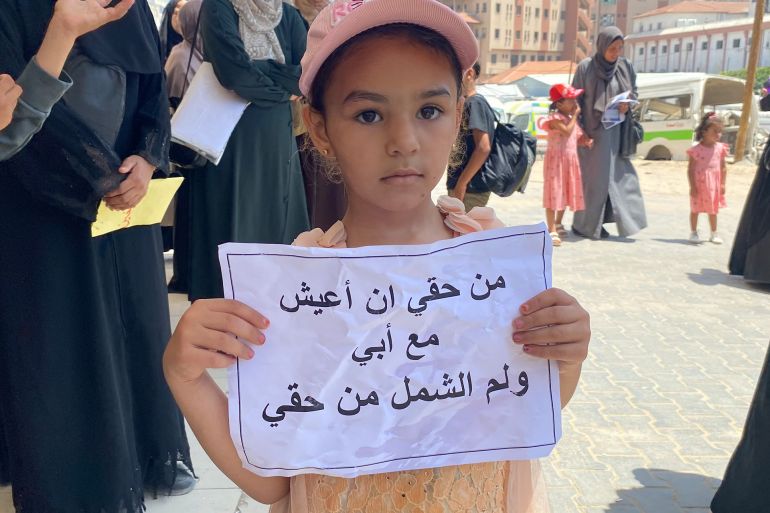 طفلة عالقة مع أسرتها ترفع لافتة "من حقي أن أعيش مع أبي"