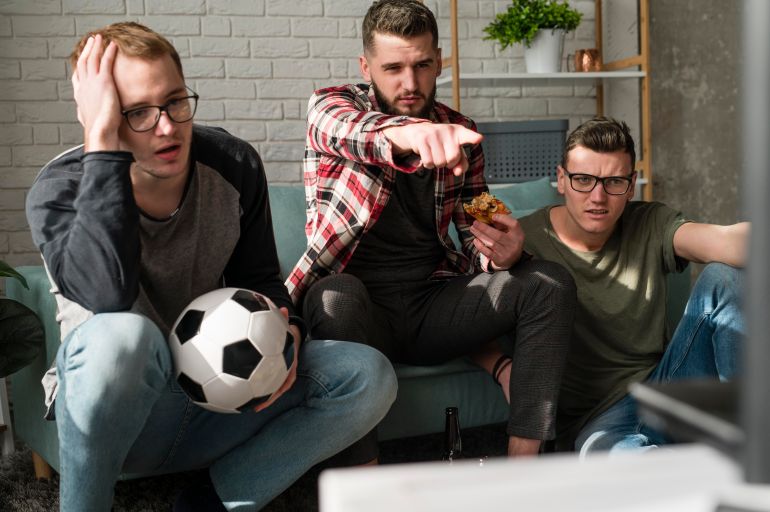 651-1-1781179415 Front view of male friends watching sports on tv with pizza and football freepik