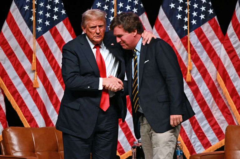 Former US President and Republican presidential candidate Donald Trump (L) shakes hands with US commentator Tucker Carlson at the end of a live interview in the finale of the Tucker Carlson Live Tour at Desert Diamond Arena in Glendale, Arizona, on October 31, 2024. (Photo by Patrick T. Fallon / AFP) (Photo by PATRICK T. FALLON/AFP via Getty Images)