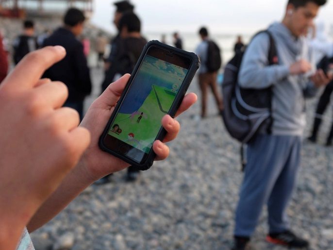 People walk with their mobile phones as some play Pokemon GO at La Punta beach in Callao, Peru, October 29, 2016. REUTERS/Mariana Bazo