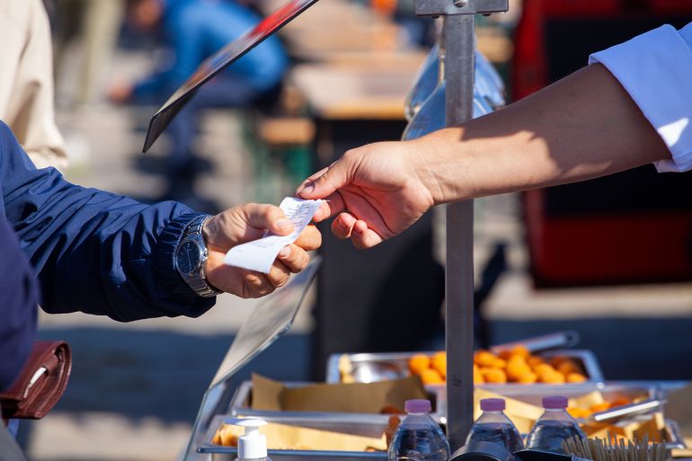 Close up of the hands of the shopkeeper who passes the sales receipt to the buyer